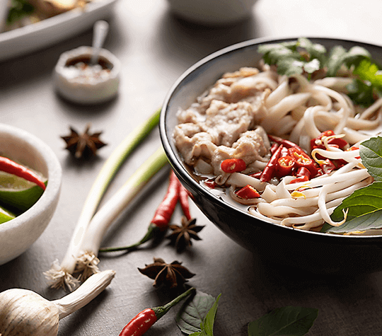 Asian noodle bowl with chili peppers, limes, and garlic