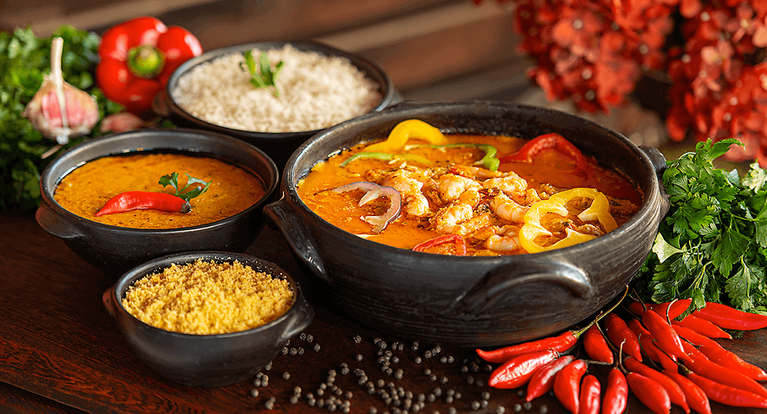 Bowl of curry with peppers and toppings nearby